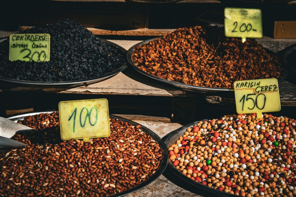 Colorful display of dried fruits and nuts in market with price tags, ideal for culinary and travel themes.
